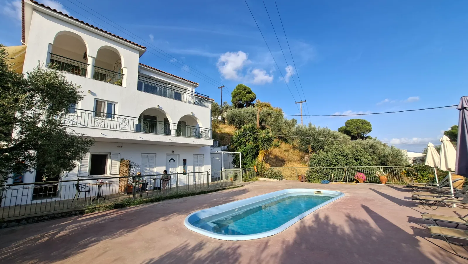 Family-Owned Studios in Agia Paraskevi with arched balconies and a quiet outdoor pool surrounded by olive trees.