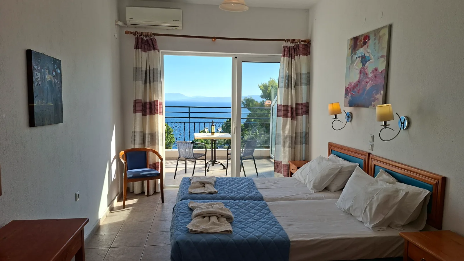 Spacious wide view of the Ninareti Superior Studio, highlighting the two twin beds and overall room layout with the sea view visible through the balcony door.